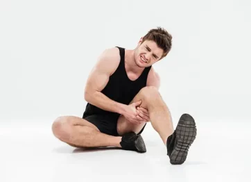 Laki-laki dalam setelan jogging memegangi pahanya karena Piriformis Syndrome yang membuat kakinya kesemutan