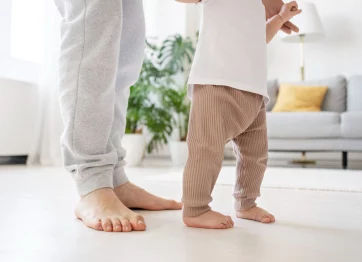 Seorang Orang Tua Membimbing Anaknya Yang Masih Kecil Saat Berdiri Dengan Tulang Kakinya