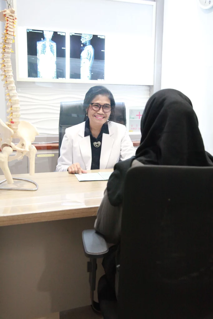 Dokter spesialis rehab medik sedang melakukan konsultasi dengan seorang klien perempuan berjilbab